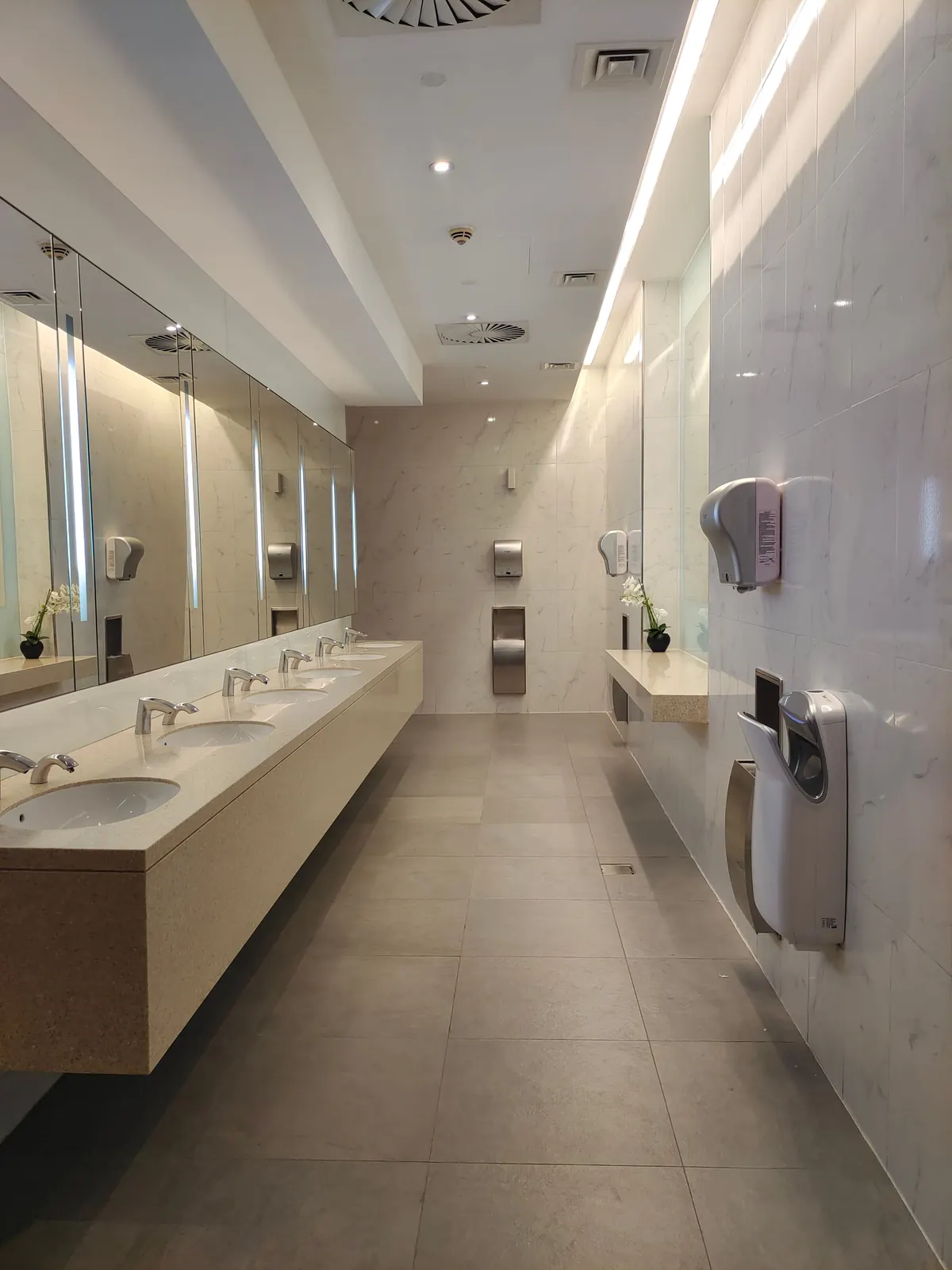 High-use public washroom with multiple basins and metal fixtures