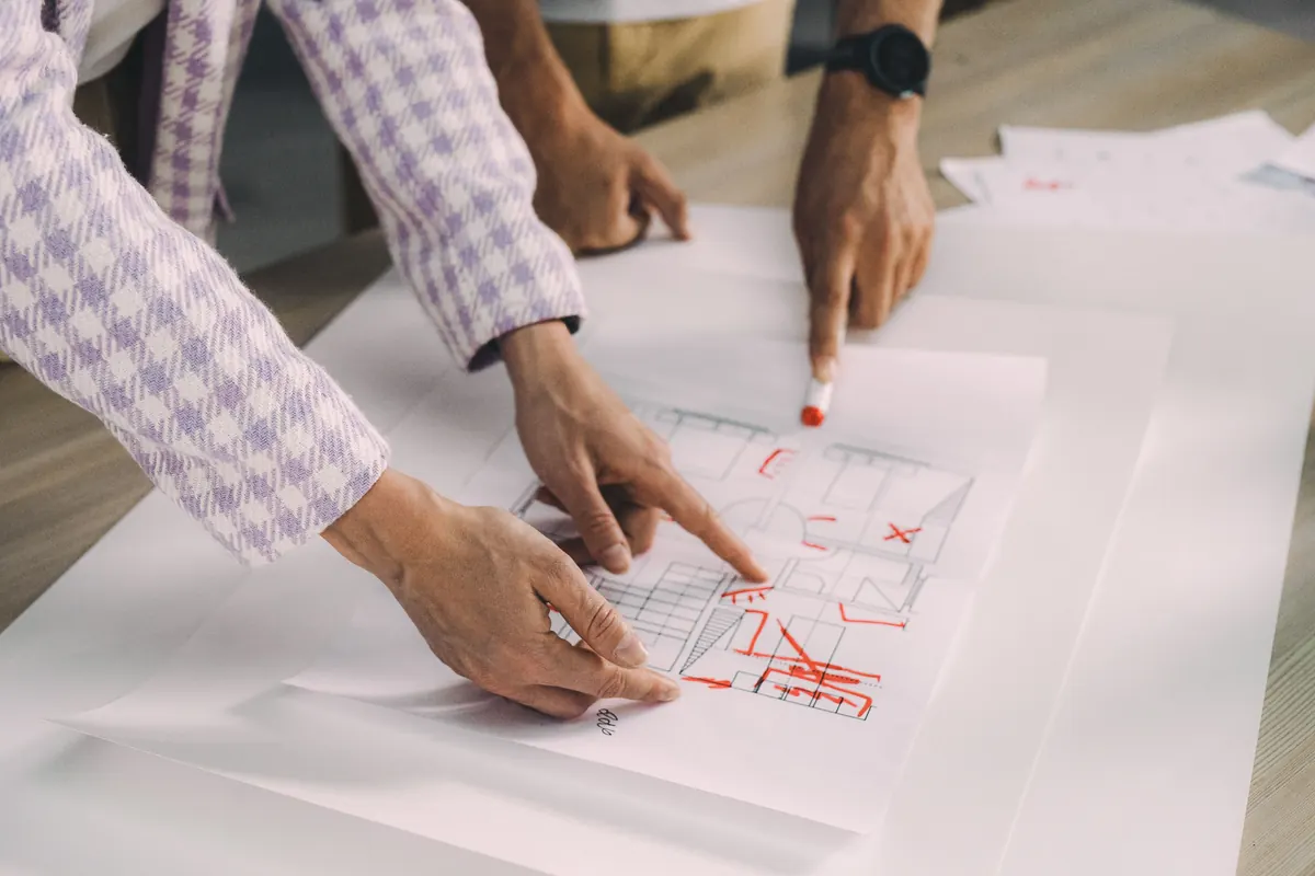 Hands reviewing a marked-up product and room plan