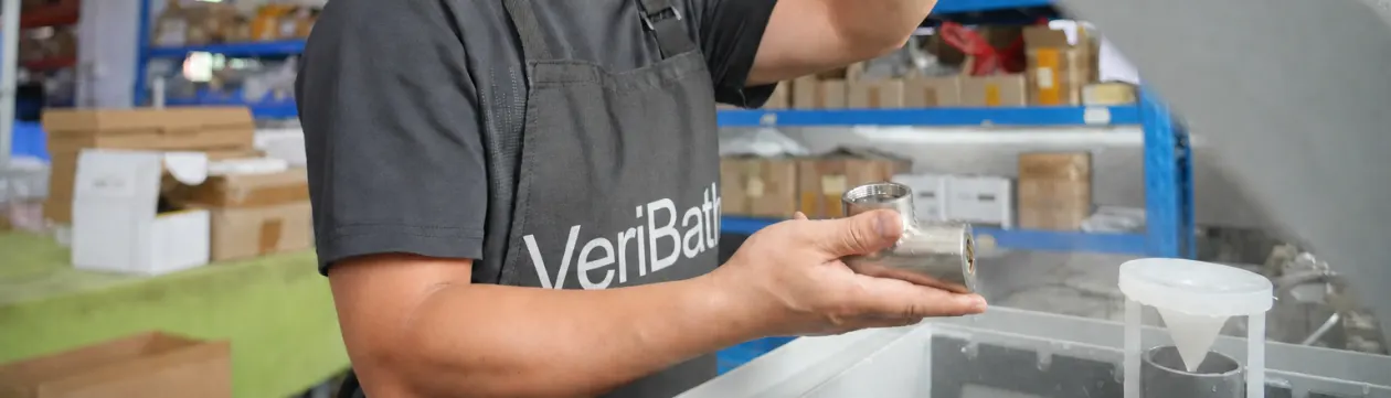 VeriBath staff member checking a stainless steel fitting at the leak test tank