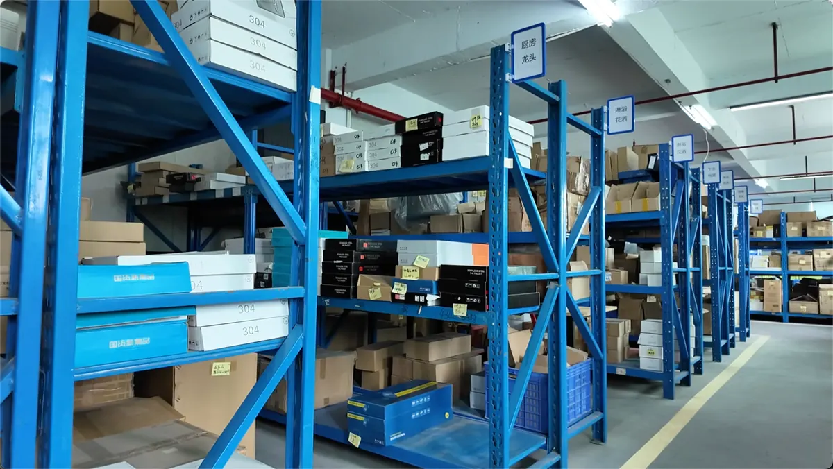 Blue storage racks with labeled bathroom hardware parts and packed products in a factory storage area