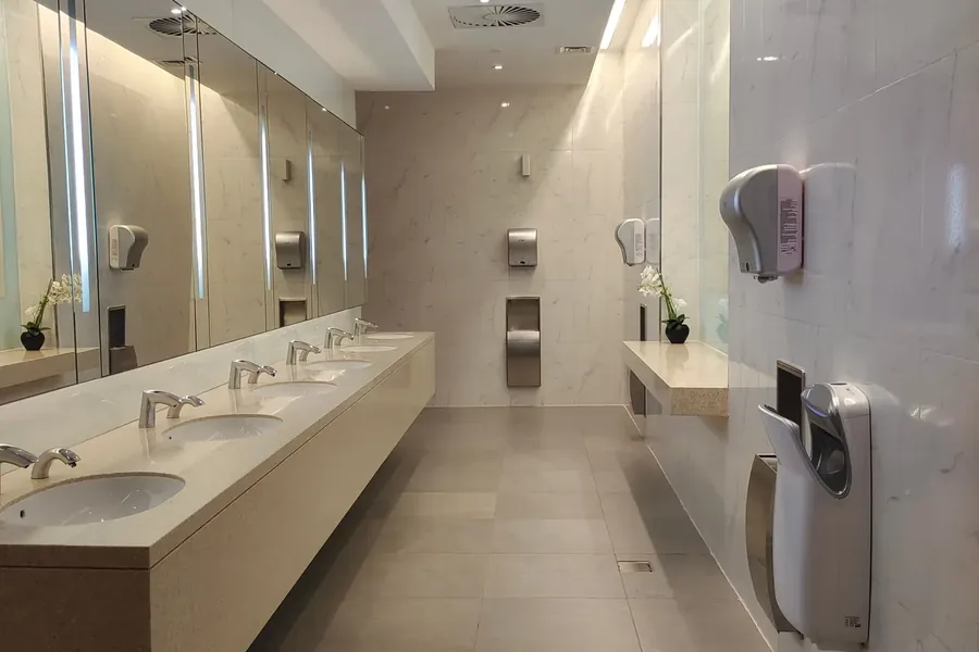 Public washroom with multiple basins, dispensers, and hand dryers
